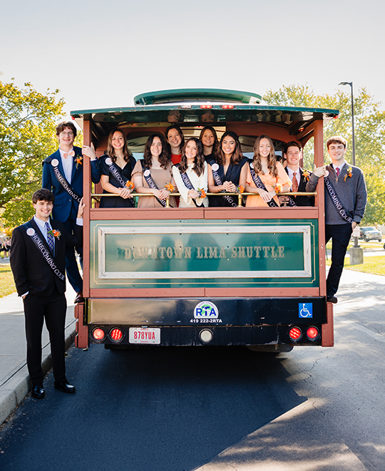 big group homecoming court pairs posing on the back of downtown lima shuttle