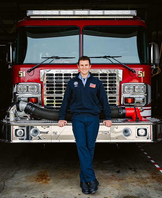Michael leaning against the front of the fire truck