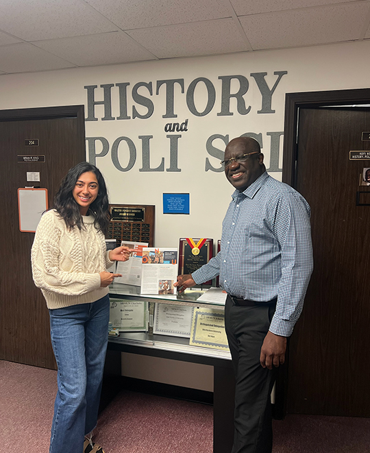 Simran and an older person pointing to a social studies education paper