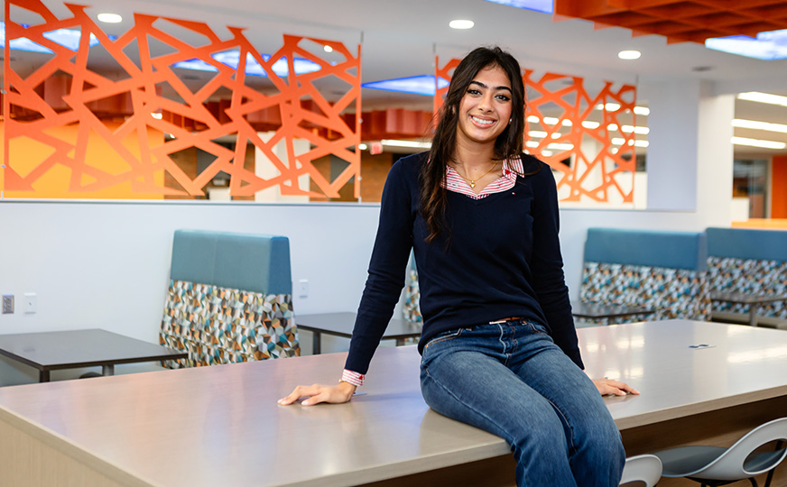 Simran seated on a table in an eatery