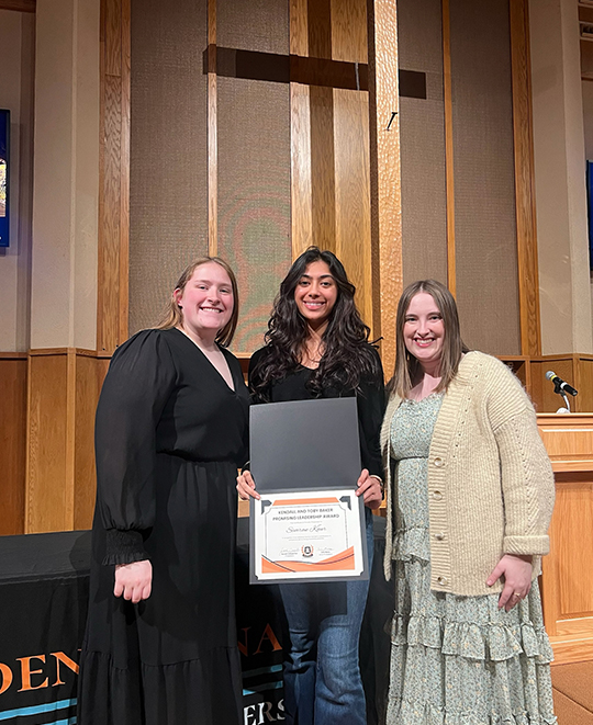 3 gals posing together with the center woman holding out an award - promising leadership award