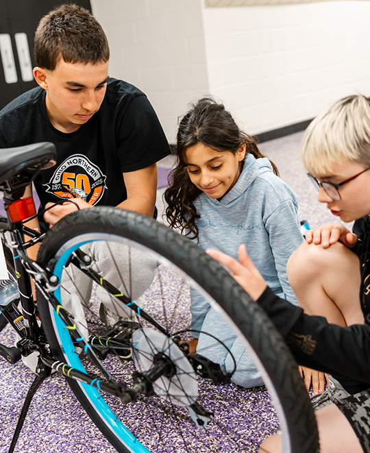 An adult person is working with 2 children explaining the function of the chain
