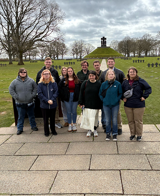 Ohio Northern University students and faculty standing among the rows of white marble crosses at the Normandy American Cemetery in France during their World War II memory tour.