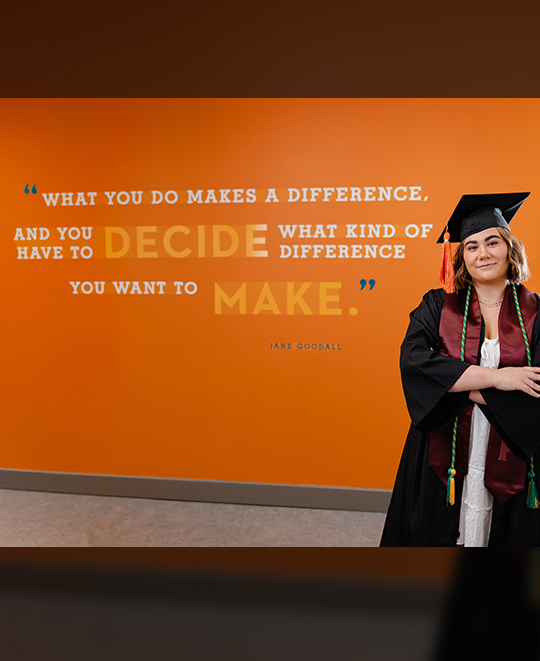 Madison posing next to jane goodall quote on the wall, "what you do makes a difference"