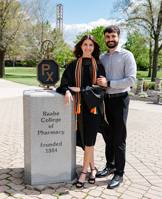 Samantha posing by the Raabe College of Pharmacy outdoor sign with her fiance