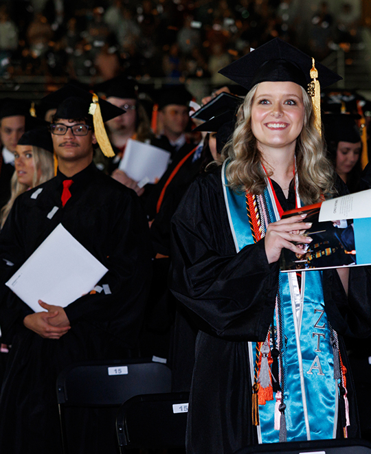 ONU graduate wearing a bright teal stole in a sea of other graduates
