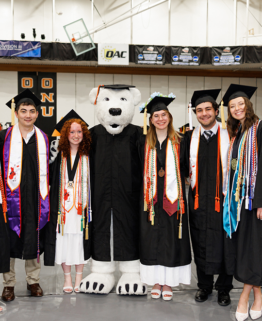 Several ONU graduates posing with Klondike all wearing caps and gowns