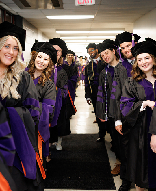 ONU Law graduate in 2 rows in the hall peeking in to see the photographer