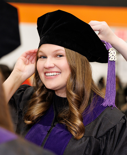 ONU Law student getting help putting her tassel on her black velvet graduation tam
