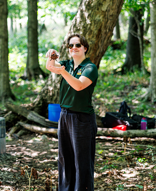 ONU student standing in a wooded area during the turtle release.