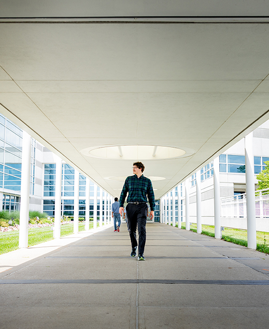Chase McCluskey walking down a spacious campus hallway.