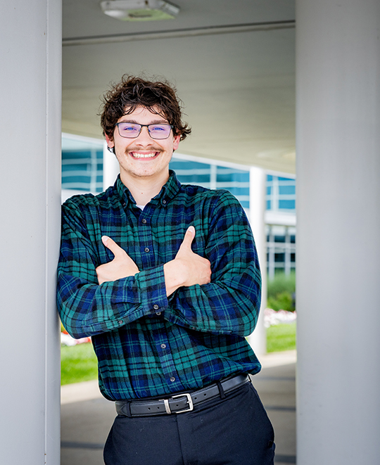 Chase McCluskey standing indoors with arms crossed, smiling at the camera.