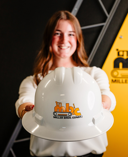 Emersyn Gerken holding a hard hat out towards the camera