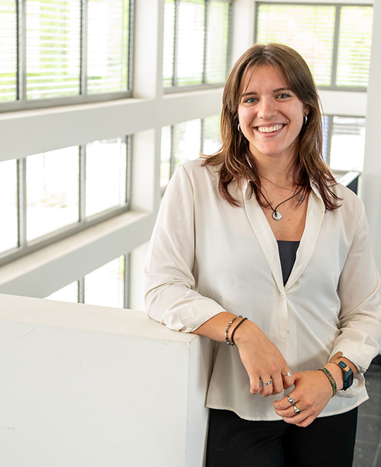 Maddie Whitewolf smiling in a professional jacket and blouse with windows in the background.