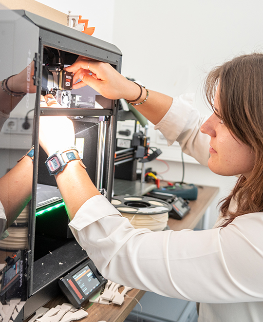 Maddie Whitewolf operating machinery in a laboratory setting while working on 3D printing equipment.