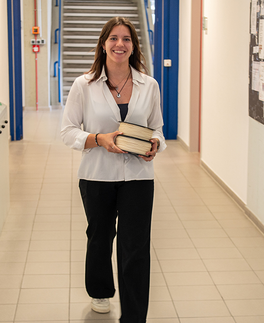Maddie Whitewolf standing and holding binders in a hallway.