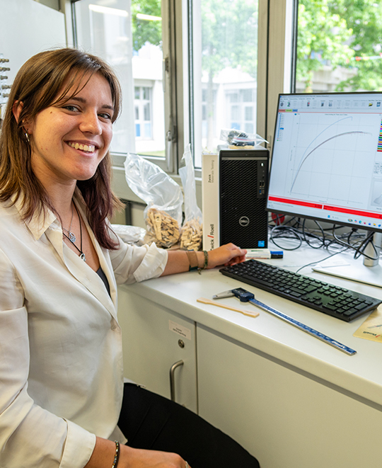 Maddie Whitewolf smiling at a computer workspace inside a laboratory setting.