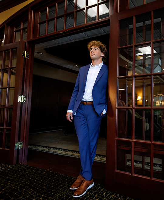 Ohio Northern University student Tyler Wood standing in a blue suit in a wooden door frame.