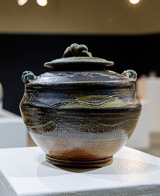 Ceramic vessel with a glossy dark lid and earthy glazed stoneware body crafted by Bruce Chesser.