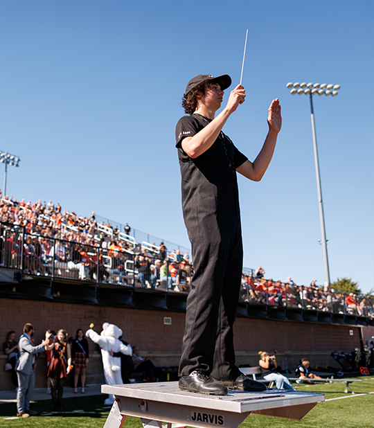 Liem Watkins conducting the ONU Marching Band on the field with a baton for the homecoming game