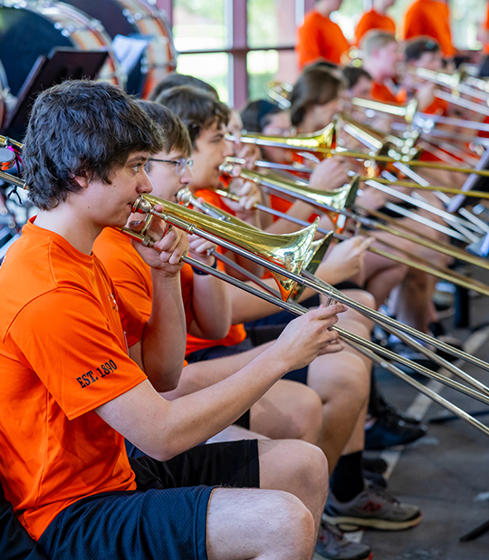Liem Watkins with marching band members playing his trombone.