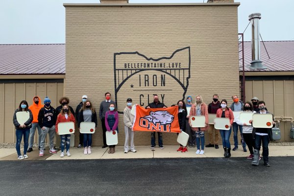 Students and alumni posing in front of outdoor mural