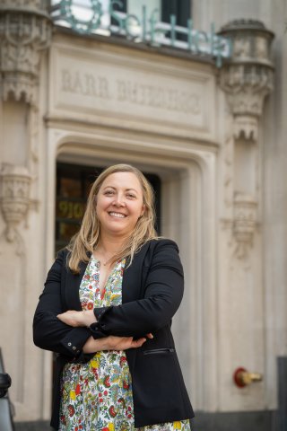 Nicole posing in front of a brick building with the text Barr Building above her