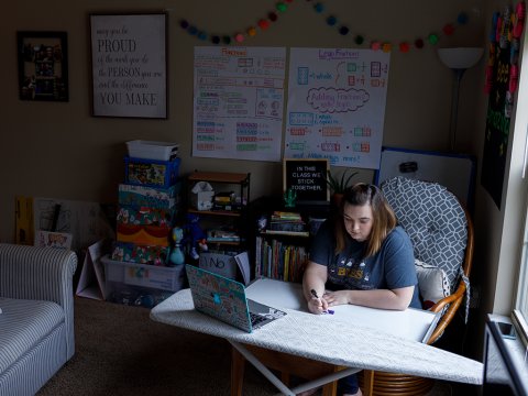 Teacher seated at a desk in her in-home workspace