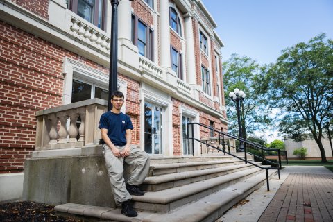 Photo of Alex sitting on outdoor stairs