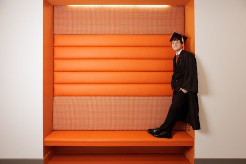 Photo of Jacob leaning against a orange space