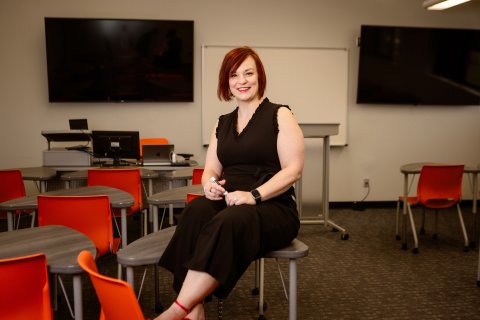Photo of Amanda seated on a school desk