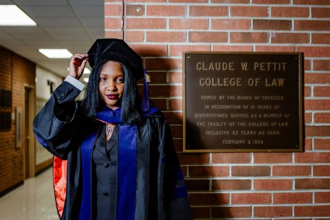 Photo of Camilla posing next to Claude W. Pettit College of Law plaque.