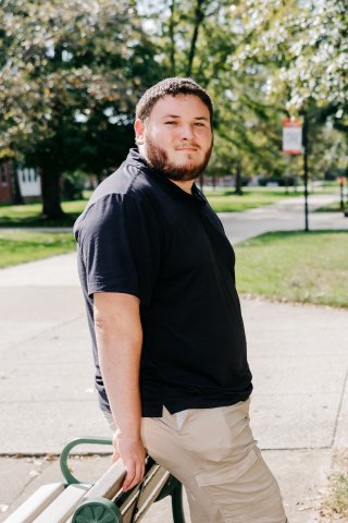 Photo of Nathaniel leaning against a bench