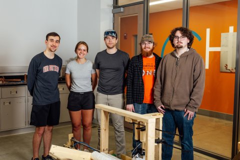 ONU team of 5 people posing behind their capstone project