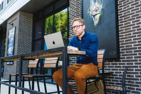 Kevin Cramer seated on a high top table working on a computer