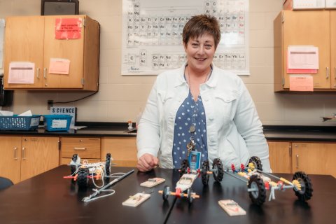 Photo of Ann with built tinker toy vehicles on a table in front of her