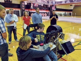 Young man with cerebral palsy operating a basketball launcher