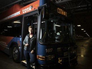 Woman standing in front of transit bus