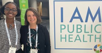 Photo of Duodo and Deprieto Mager posing next to an I am public health sign