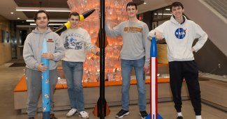 Photo of 4 ONU students next to their rockets