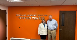Peter and Margaret Bigelow pose in front of testing center signage @ ONU