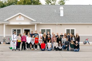 A group of college students posing in front of a daycare building