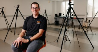 Photo of Josh seated in front of many tripods