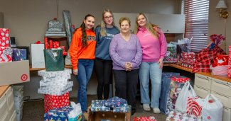 Photo of 2 ONU staff and 2 students with many presents around them