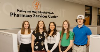 Photo of ONU students in front of Pharmacy sign on the wall