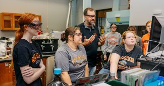 Photo of ONU students in a lab in front of a computer monitor with a faculty member behind them