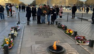 Eternal Flame with 2 rows of flowers beside it and people on the end
