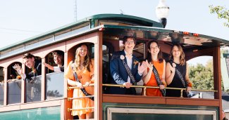 2025 ONU homecoming court in a green tram waving 