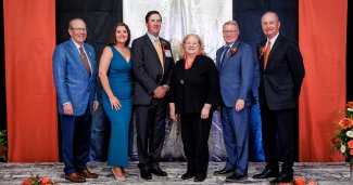 Six Ohio Northern University Distinguished Alumni Award honorees smiling and posing together on stage during the Homecoming & Reunion Weekend ceremony.