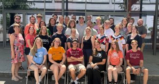 A group of young musicians and performers posing together outdoors during a summer music program.